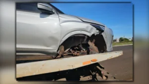 acidente em Arapongas mostrando a roda dianteira do carro Nissan Kicks desprendida no gramado ao lado do poste quebrado na Rua Tico-Tico-Rei sob a luz do dia.
