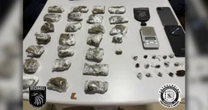 Disk-drogas em Arapongas mostrando a motocicleta apreendida e as porções de maconha enfileiradas sobre a mesa da delegacia de plantão.