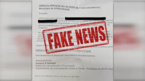 Foto de uma falsa notificação impressa com o título "Irregularidade no Alvará de Funcionamento". O documento em papel branco possui marcas de rasura em dados confidenciais e exibe um grande carimbo vermelho centralizado com o texto "FAKE NEWS", alertando sobre o golpe do alvará falso.