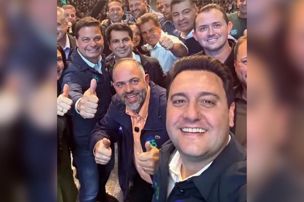 Ratinho Junior e Sandro Alex juntos em um evento político do PSD Paraná em Guarapuava, com a bandeira do partido e a logo do evento ao fundo.