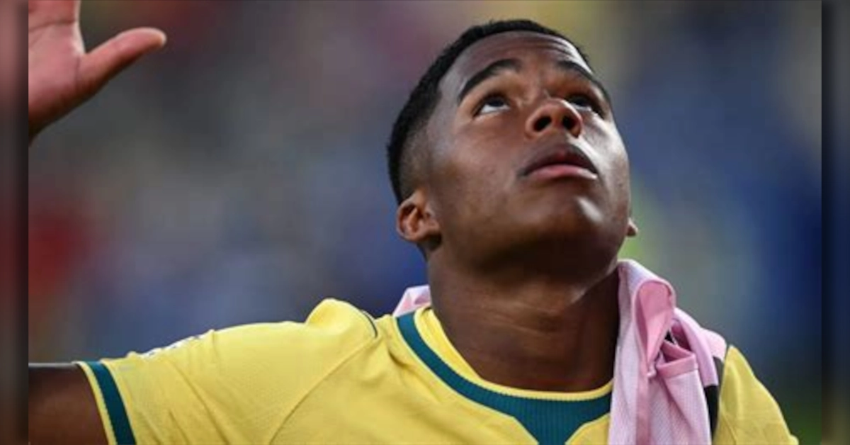 Atacante Endrick sentado no banco de reservas com o colete da seleção brasileira durante treinamento.