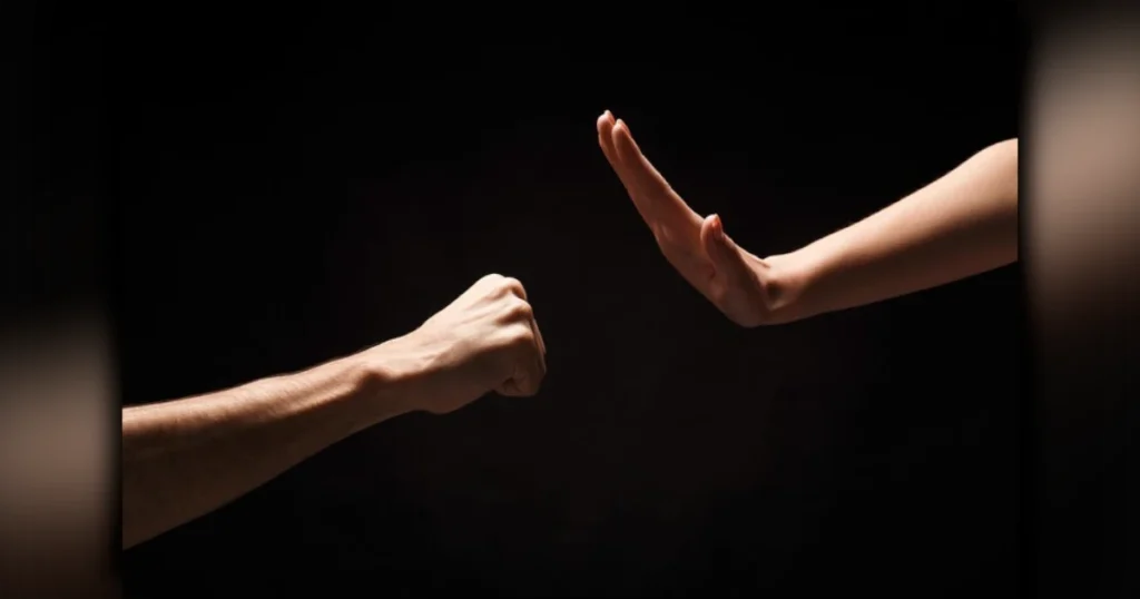 Violência doméstica em Arapongas mostrando as mãos de um homem detido atrás das grades de uma cela policial durante o dia.