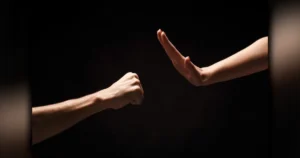 Violência doméstica em Arapongas mostrando as mãos de um homem detido atrás das grades de uma cela policial durante o dia.